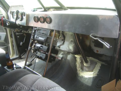 1990 Ford Bronco - Passenger side of a gutted race-vehicle cab with brushed-aluminum dash, gauges, roll-cage tube and bare floor.