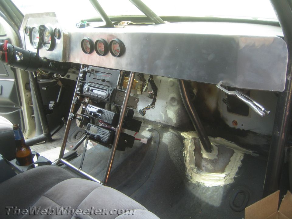 Passenger side of a gutted race vehicle interior with aluminum dash and roll cage