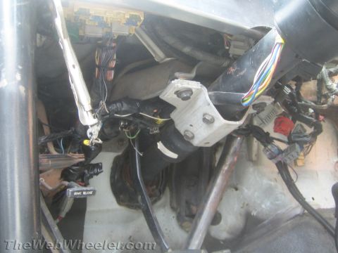 1990 Ford Bronco - Dense wiring harnesses, connectors and a steering/pedal bracket exposed inside a stripped vehicle footwell.