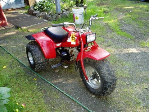 2000 Ford E350 - This red ATV is parked on a grassy area next to a gravel path.