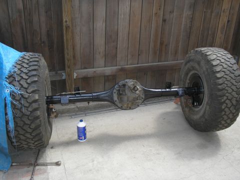 1990 Ford Bronco - Rear axle assembly with tires, likely for an off-road vehicle, is shown on a concrete surface.