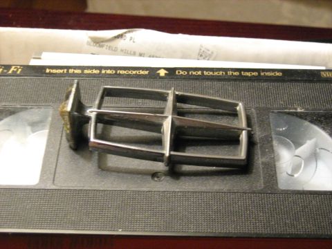 1988 Mercury Grand Marquis - A car emblem rests on a VHS tape, with visible text instructions.