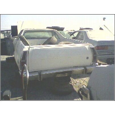 1973 Ford Ranchero - A white pickup truck sits in a junkyard with other vehicles visible.