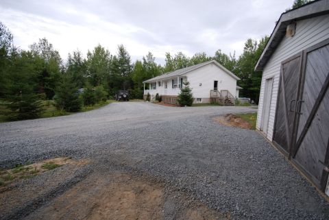 1996 Ford Bronco - A dark colored Jeep Wrangler is parked on a gravel driveway in front of a white house and a detached garage.