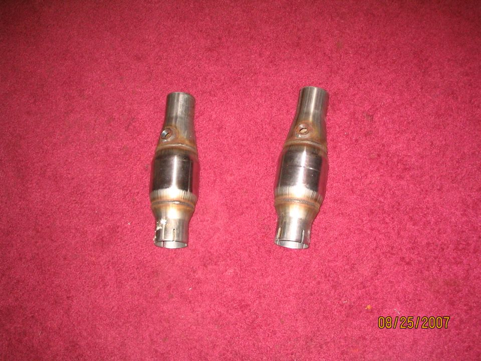two metal catalytic converters on a red surface