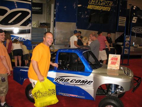 1995 Ford C-350 (Centurion Conversions) - A man smiles next to a display RC truck at an event.