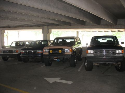 1995 Ford C-350 (Centurion Conversions) - Four SUVs are parked in a lot, showing their front views. The vehicles appear to be Ford Broncos and an F-Series truck.