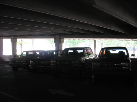 1995 Ford C-350 (Centurion Conversions) - A lineup of trucks, including a 1995 Ford C-350 (Centurion Conversions), are parked under a covered structure.