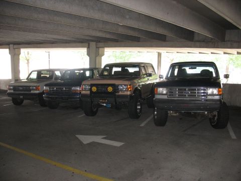1995 Ford C-350 (Centurion Conversions) - Four Ford trucks are parked in a garage, one of which is a 1995 Ford C-350 (Centurion Conversions).