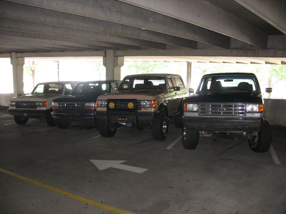 Four Ford trucks parked in a garage, including a 1995 Ford C-350 (Centurion Conversions)