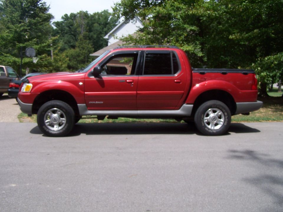 Side view of a red 2002 Ford Sport Trac pickup truck parked on a street