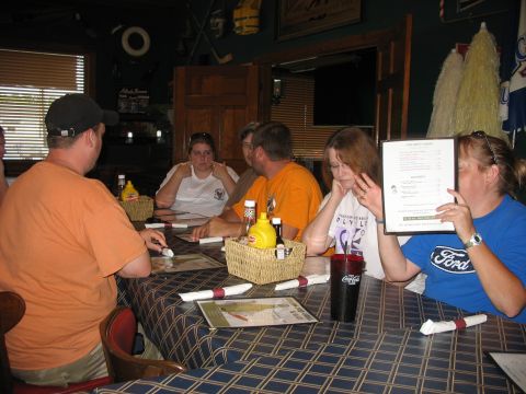 1995 Ford C-350 (Centurion Conversions) - A group of people are seated at a table in a restaurant, with one person holding up a menu that displays a Ford logo.