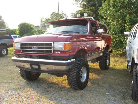 1995 Ford C-350 (Centurion Conversions) - This lifted red Ford Bronco has a custom visor with lights and large off-road tires.