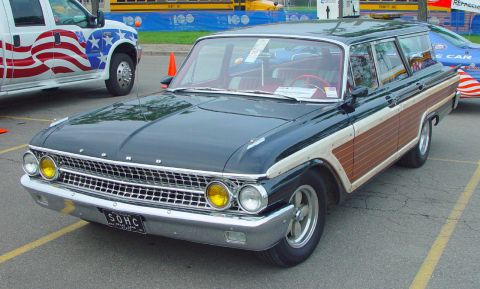 1969 Ford Fairlane - A classic Ford station wagon wood grain paneling is parked next to a truck with an American flag design.