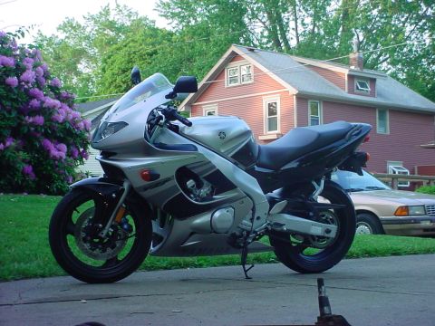 2004 Yamaha FZR600 - A silver and black 2004 Yamaha FZR600 motorcycle is parked on a driveway next to a flowering bush.