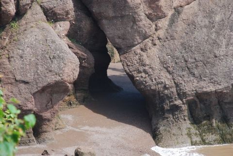1996 Ford Bronco - Natural rock formations create an opening on a sandy beach with gentle waves washing ashore.
