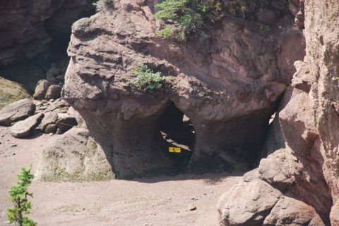 1996 Ford Bronco - Natural rock formations create a cave entrance, with a yellow sign partially visible within the darkness.