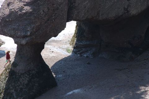 1996 Ford Bronco - A person walks near unusual rock formations on a sandy shore.