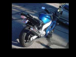 2004 Yamaha FZR600 - A blue sport motorcycle is parked on an asphalt surface next to a car.