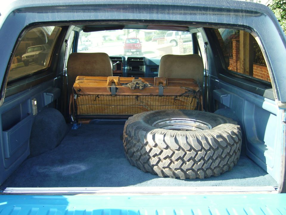 Cargo area of an SUV with rear seats folded, a spare tire and a toolbox inside