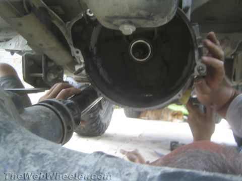1987 Suzuki Samurai - Mechanics work on the transmission of a vehicle, likely during a swap or repair.