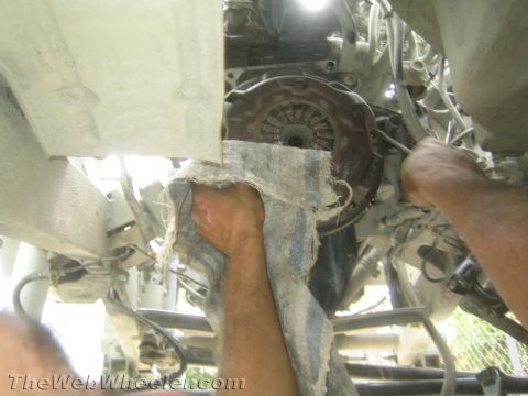 1987 Suzuki Samurai - Mechanic works on a vehicle's transmission and clutch assembly, possibly during a swap.