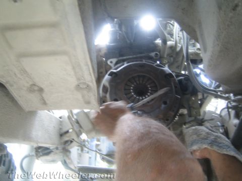 1987 Suzuki Samurai - Mechanic works on the clutch assembly of a vehicle, likely during a transmission swap.