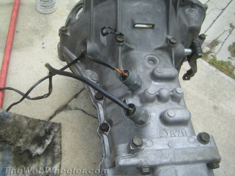 1987 Suzuki Samurai - A close-up view of a transmission housing with electrical sensors and wiring attached.