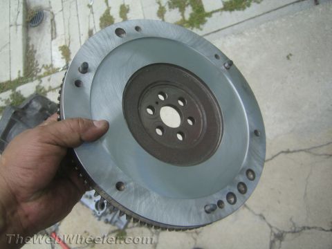 1987 Suzuki Samurai - A hand holds a metal flywheel, a component of a vehicle's transmission system.