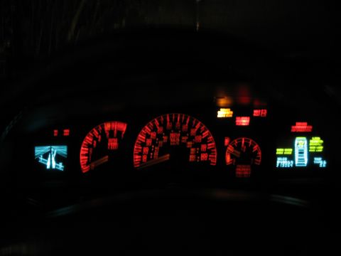 1992 Ford Crown Victoria - Illuminated car dashboard gauges and digital displays glow red and blue in the dark.
