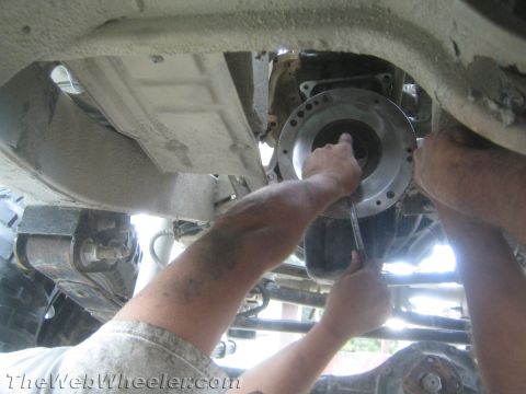 1987 Suzuki Samurai - Mechanics are working on the transmission of a vehicle, likely performing a clutch or transmission swap.