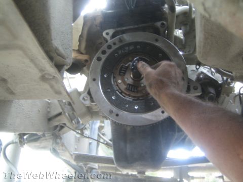 1987 Suzuki Samurai - Mechanic's hand installing a clutch disc onto the flywheel of a vehicle's transmission.