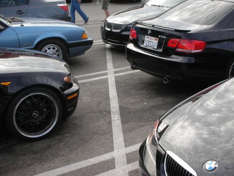 1998 Ford Crown Victoria - A black BMW 335i is parked in a lot, showing its rear end and California license plate.
