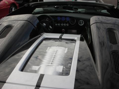 1998 Ford Crown Victoria - A black Ford GT convertible with racing stripes is parked next to a red Ferrari.