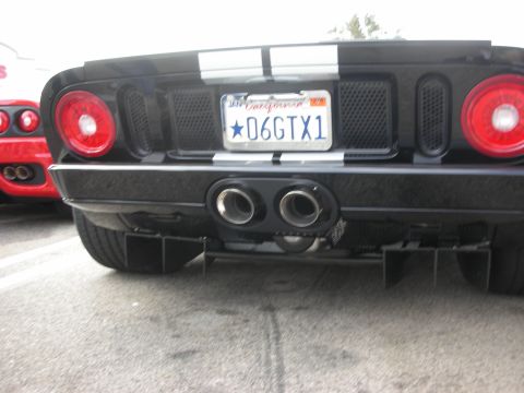 1998 Ford Crown Victoria - The rear of a black Ford GT with racing stripes is visible, parked next to a red Ferrari.