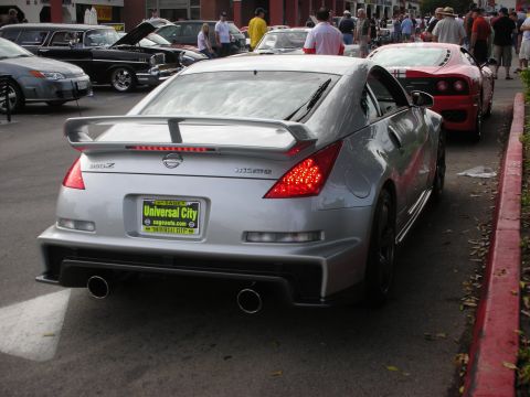 1998 Ford Crown Victoria - A silver Nissan 350Z is parked on the street next to a red Ferrari.