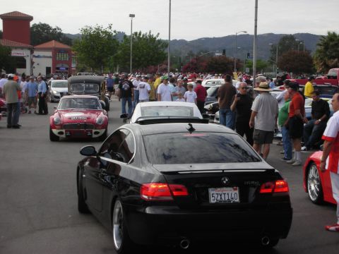 1998 Ford Crown Victoria - A gathering of cars and people at an outdoor event, with a black BMW coupe prominently featured.