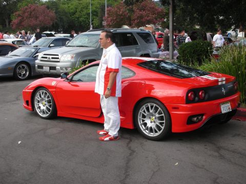 1998 Ford Crown Victoria - A man stands beside a red Ferrari 360 Modena at an outdoor car meet.
