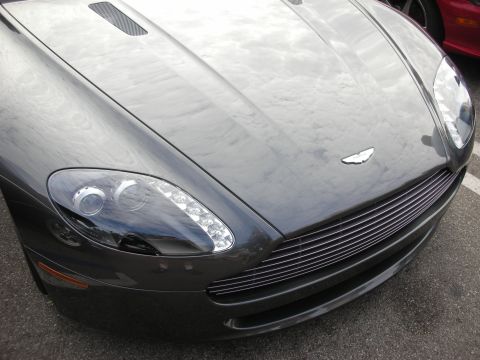 1998 Ford Crown Victoria - The front of a dark gray Aston Martin is shown, with a glimpse of another vehicle in the background.