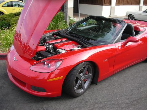 1998 Ford Crown Victoria - A red convertible Corvette with its hood open, revealing the engine. A yellow car is visible in the background.
