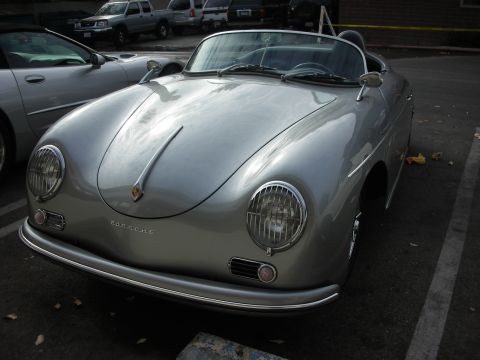 1998 Ford Crown Victoria - A classic silver Porsche 356 Speedster is parked in a lot, with other vehicles visible in the background.