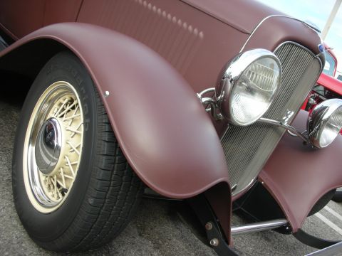 1998 Ford Crown Victoria - A close-up view of the front of a classic car, highlighting its distinctive fender and wire-spoke wheel.