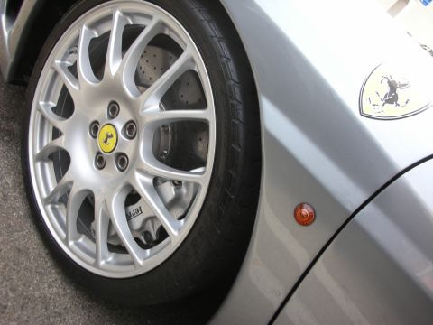 1998 Ford Crown Victoria - Close-up of a silver Ferrari wheel and fender, showing the prancing horse emblem and brake caliper.