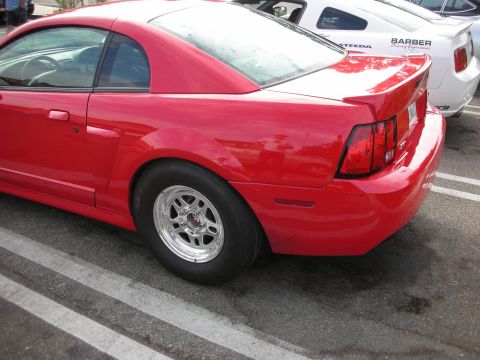 1998 Ford Crown Victoria - Rear view of a red Ford Mustang modified with drag radial tires, parked beside another vehicle.