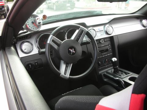 1998 Ford Crown Victoria - The interior of a Ford Mustang features a prominent tachometer and the iconic Mustang emblem on the steering wheel.