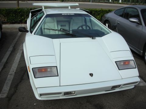 1998 Ford Crown Victoria - A white Lamborghini Countach is parked next to a silver car, with a "Support Our Troops" sticker visible on its windshield.