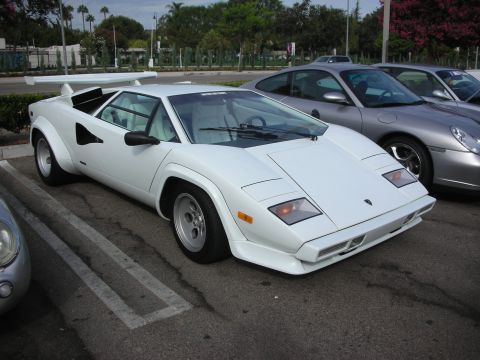 1998 Ford Crown Victoria - A white Lamborghini Countach is parked in a lot, with a silver Porsche and another vehicle visible beside it.