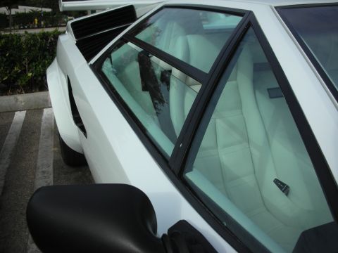 1998 Ford Crown Victoria - Close-up of a white sports car's interior and side mirror, showing quilted seats.