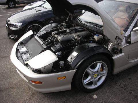 1998 Ford Crown Victoria - A silver Ferrari's engine bay is exposed, with a black BMW parked behind it.