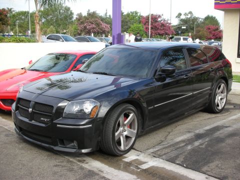1998 Ford Crown Victoria - A black Dodge Magnum SRT8 is parked in a lot, with a red sports car to its left.